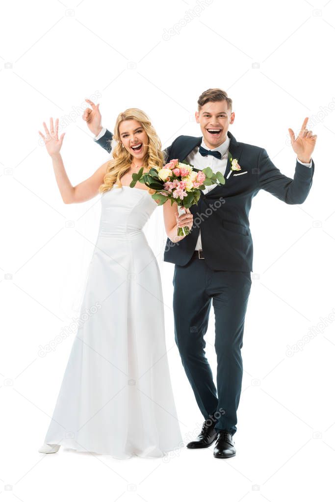 cheerful bride and groom waving hands while looking at camera isolated on white