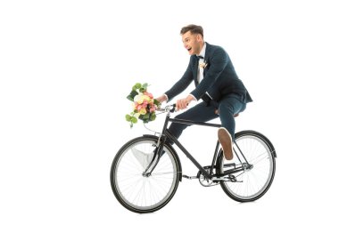 happy groom in elegant suit and sneakers riding bike while holding wedding bouquet isolated on white clipart