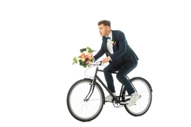 cheerful groom in sneakers riding bike and holding wedding bouquet isolated on white clipart