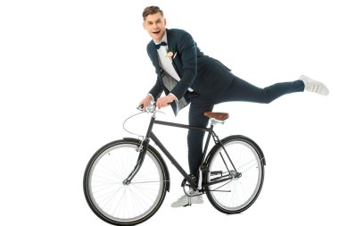 cheerful groom in elegant suit making stunts on bike isolated on white clipart