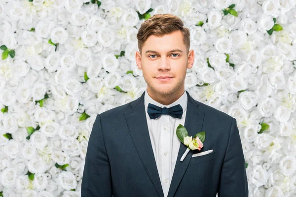 Handsome Groom Elegant Jacket Boutonniere Looking Camera White Floral Background — Stock Photo, Image