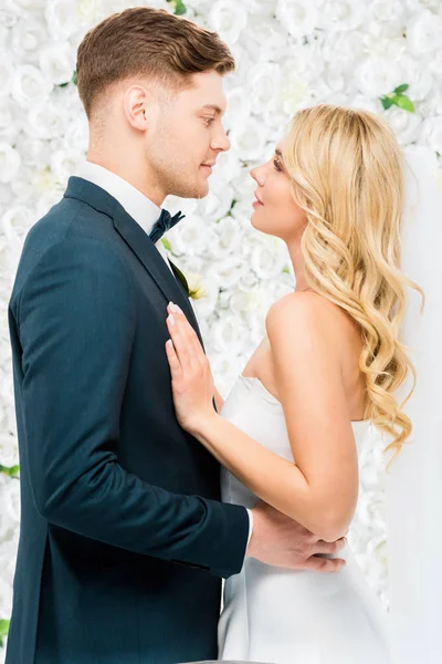 Felice Giovane Sposa Sposo Piedi Faccia Faccia Sfondo Floreale Bianco — Foto Stock