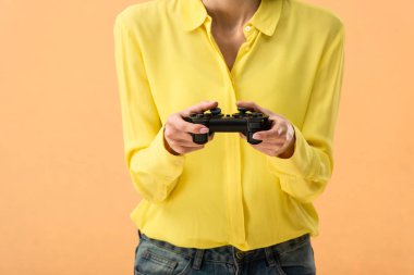 Sarı tişört gamepad üzerinde turuncu izole tutan kadının kırpılmış görünümü