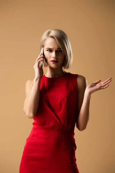Upset Blonde Girl Red Dress Talking Smartphone Isolated Beige — Stock Photo, Image