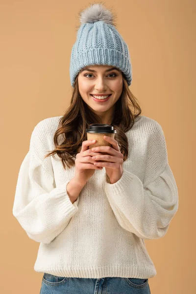 ベージュに分離されて笑顔で一杯のコーヒーを保持している白いセーターでうれしそうなブルネットの少女 — ストック写真