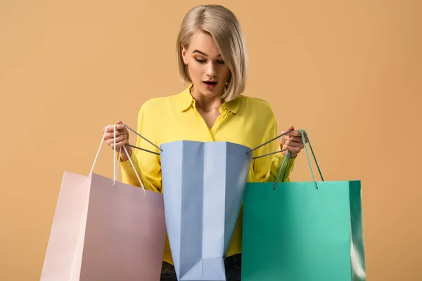 Shocked Blonde Woman Looking Shopping Bag Isolated Beige — Stock Photo, Image