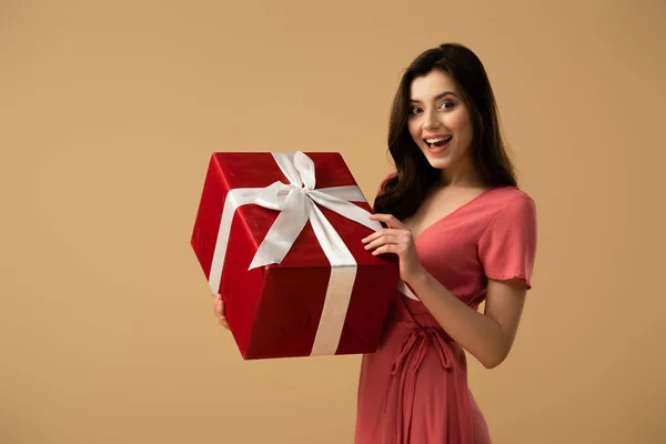 Chica Morena Sorprendida Vestido Sosteniendo Caja Regalo Roja Sonriendo Aislado — Foto de Stock