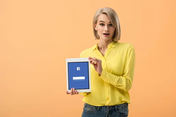 Surprised Blonde Girl Yellow Shirt Holding Digital Tablet Facebook App — Stock Photo, Image