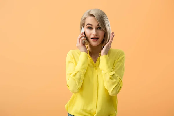 Zaskoczony Blond Kobieta Żółta Koszulka Rozmowy Smartphone Pomarańczowym Tle — Zdjęcie stockowe