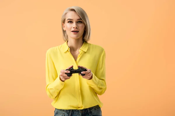 Interested Blonde Girl Yellow Shirt Holding Gamepad Isolated Orange — Stock Photo, Image