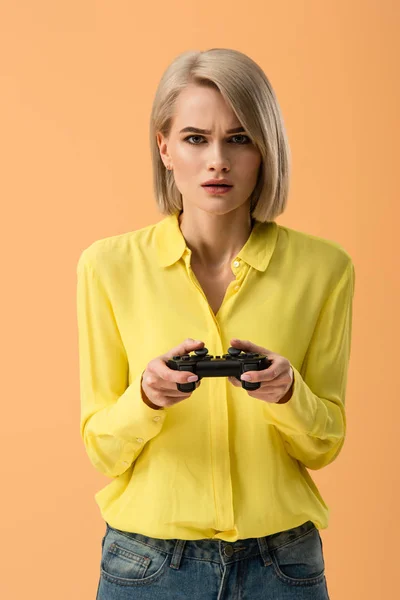 Bekymret Blondine Kvinde Gul Skjorte Holder Gamepad Isoleret Orange - Stock-foto