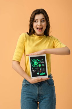 Mutlu kız üzerinde turuncu izole ekranda dijital tablet Infographic app ile tutarak