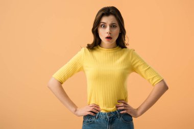 Turuncu üzerinde izole kalça üzerinde eller ile ayakta sürpriz esmer kadın 
