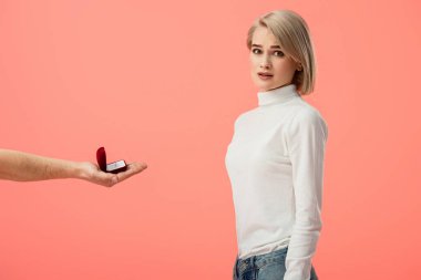 Alyans çekici sarışın kız pembe üzerinde izole yakınındaki kutusuyla tutan adamın kırpılmış görünümü