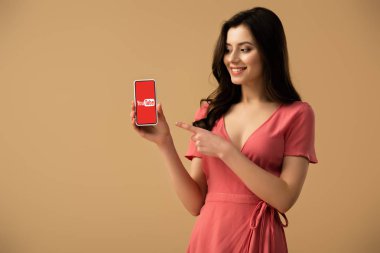 smartphone ekranında izole kahverengi üzerine youtube uygulaması ile parmak ile işaret neşeli esmer kız 