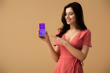 app ekranda izole kahverengi üzerine alışveriş ile smartphone, parmağınızla işaret neşeli esmer kız 