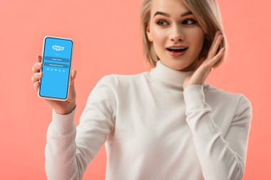 seçici odak üstünde pembe üzerinde izole perde smartphone skype uygulaması ile tutan sürpriz sarışın kadın 