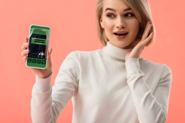 seçici odak üstünde pembe üzerinde izole perde smartphone rezervasyon uygulaması ile tutan sürpriz sarışın kadın 