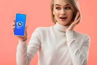 seçici odak üstünde pembe üzerinde izole perde smartphone shazam app ile tutan sürpriz sarışın kadın 