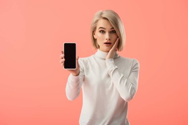 boş ekran üzerinde pembe izole ile Smartphone tutan şok genç sarışın kadın 