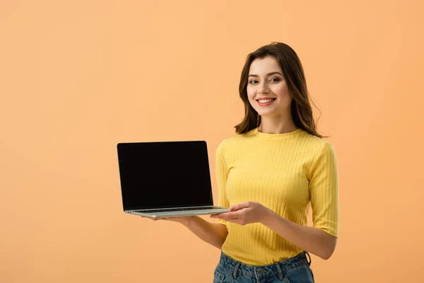 Vrolijke Brunette Meisje Met Laptop Met Leeg Scherm Geïsoleerd Oranje — Stockfoto