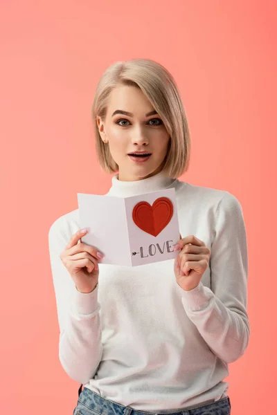 Zaskoczony Blondynka Młoda Kobieta Trzyma Kartkę Życzeniami Stojąc Różowym Tle — Zdjęcie stockowe