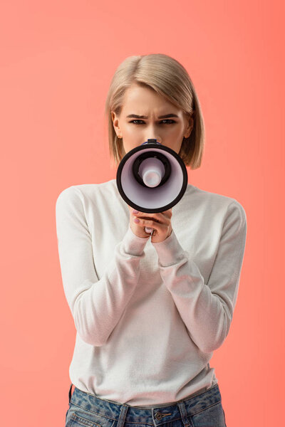 blonde young woman speaking in megaphone isolated on pink 