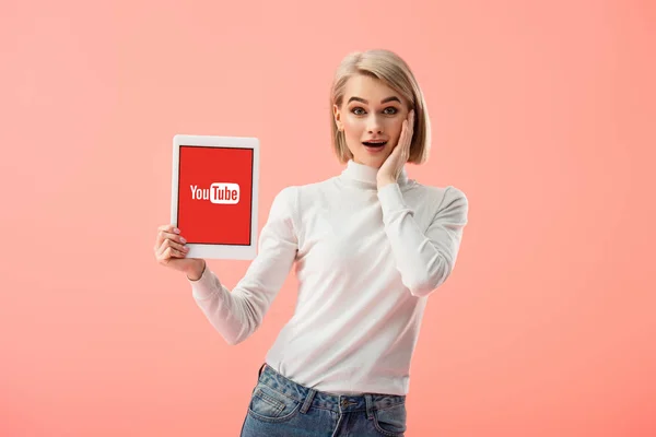 Překvapený Blond Žena Držící Digitální Tablet Aplikací Youtube Obrazovce Izolované — Stock fotografie