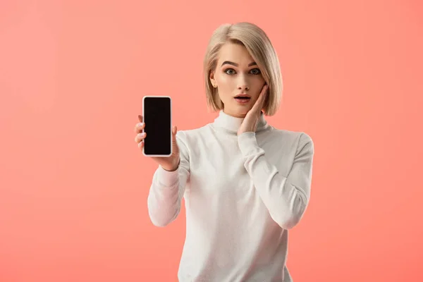 Шоке Молодая Блондинка Держит Смартфон Пустым Экраном Изолированы Розовый — стоковое фото