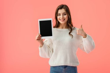 Dijital tablet boş ekran ile tutarak ve başparmak üzerinde izole pembe gösterilen mutlu genç kadın  