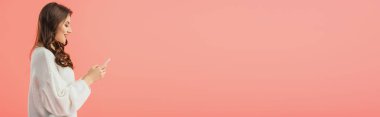 gülümseyen panoramik çekim ve beyaz kazaklı pink izole smartphone tutan çekici kadın