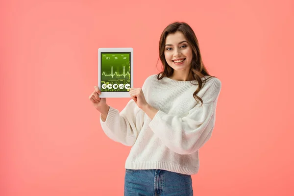 快乐的年轻女子拿着数字平板电脑与健康应用程序在屏幕上隔离粉红色 — 图库照片