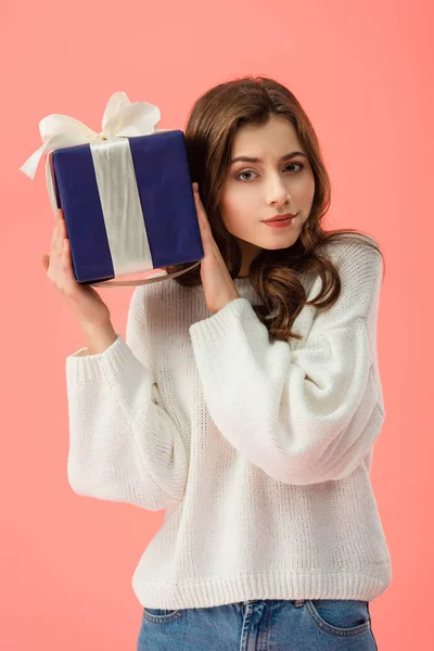 好奇和有吸引力的女人在白色毛衣举行礼品盒隔离粉红色 — 图库照片