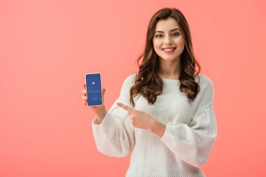 kadın beyaz kazaklı smartphone ile facebook app ekranda pink izole, parmakla işaret 