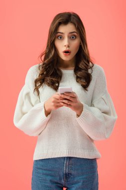 pink izole smartphone holding beyaz süveterli şok genç kadın
