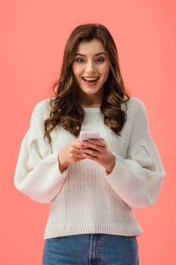 gülümseyen pink izole smartphone holding beyaz kazaklı genç kadın