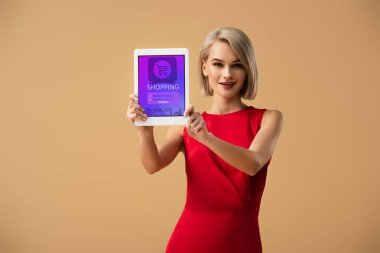app üzerinde bej izole ekranda alışveriş ile dijital tablet tutan Kırmızı elbiseli güzel kadın