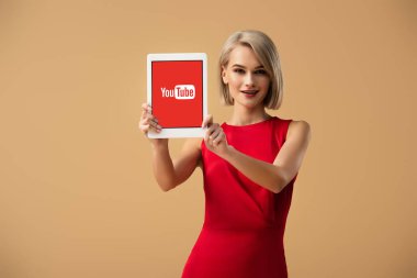 ekran üzerinde bej izole dijital tablet youtube uygulaması ile tutarak Kırmızı elbiseli güzel kadın