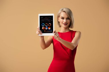 Çizelgeler ve grafikler ile dijital tablet üzerinde bej izole ekran üzerinde tutan Kırmızı elbiseli güzel kadın