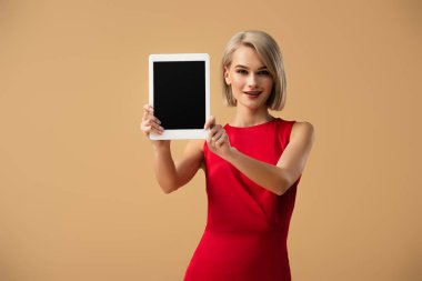 boş ekran üzerinde bej izole ile dijital tablet tutan Kırmızı elbiseli güzel kadın