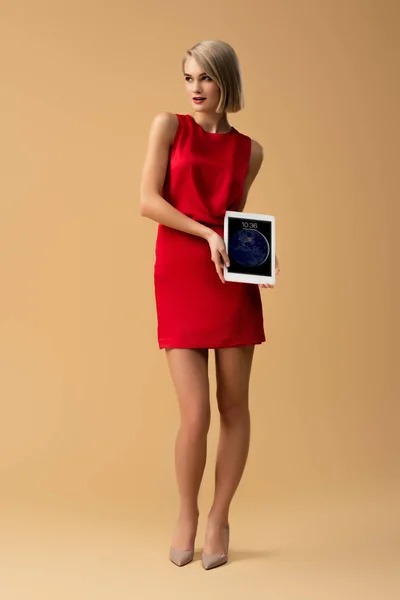ロック画面とデジタル タブレットを保持している赤いドレスを着た女性の完全な長さのビュー — ストック写真