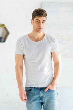 Beyaz t-shirt ve jeans beyaz arka plan üzerinde duran yakışıklı adam