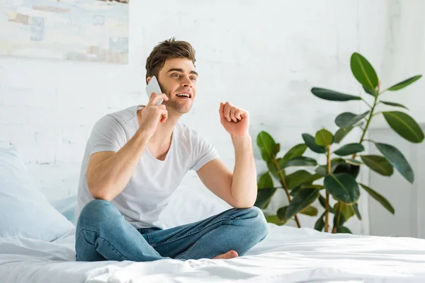 Hombre Guapo Camiseta Jeans Sentado Cama Hablando Teléfono Inteligente Dormitorio — Foto de Stock