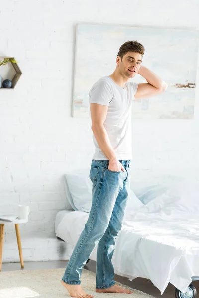 Handsome Man White Shirt Jeans Standing Bed Home — Stock Photo, Image