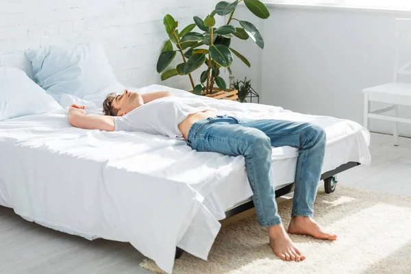 Przystojny Mężczyzna Shirt Dżinsy Leżąc Plecach Łóżko Sypialni — Zdjęcie stockowe