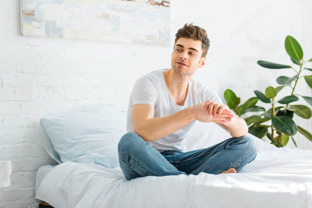 selective focus of handsome man sitting on bed at home