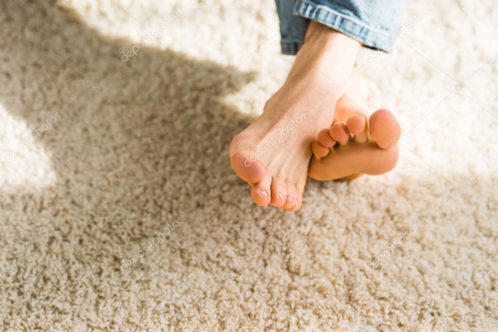 cropped view of male feet on beige rug