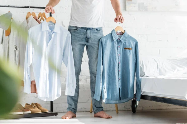 Cropped View Man White Shirt Standing Bed Holding Shirts Bedroom — Stock Photo, Image