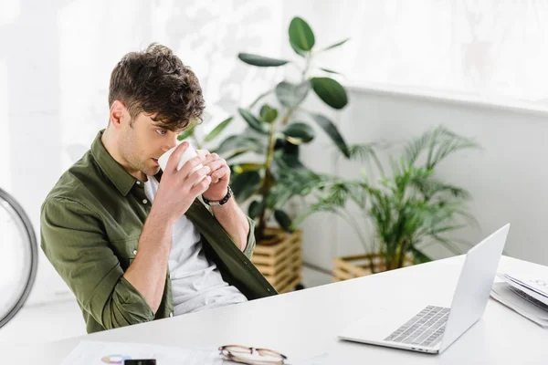 Επιχειρηματίας Πράσινο Πουκάμισο Κάθεται Στο Τραπέζι Laptop Και Πίνει Καφέ — Φωτογραφία Αρχείου