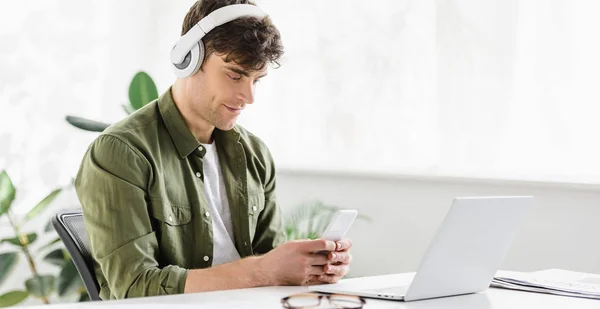 Stilig Affärsman Hörlurarna Sitter Nära Bordet Med Laptop Och Hålla — Stockfoto